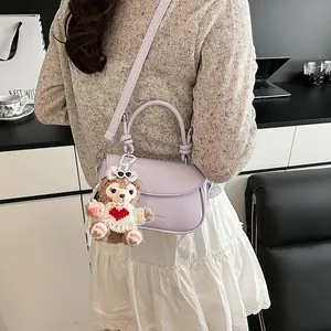 Vue arrière d'un sac besace lavande avec bandoulière et breloque en peluche