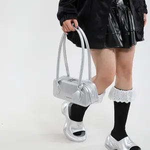 Detail of silver metallic handbag with dual handles and printed logo on the front