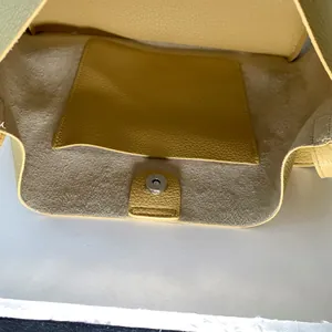 Close-up of yellow lychee leather tote bag interior with magnetic buckle and pocket