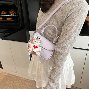 Détail d'un sac bandoulière brillant lilas avec poignée nouée et breloque en peluche