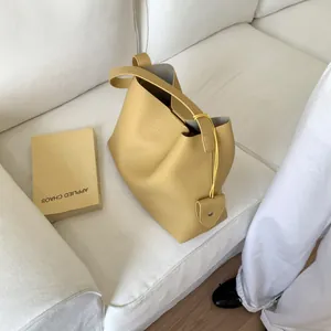 Detail view of mustard yellow bucket bag featuring lychee grain leather and heart charm