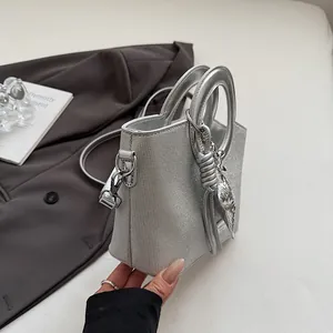 Gros plan du sac seau à paillettes argentées avec poignée métallique sur blazer gris