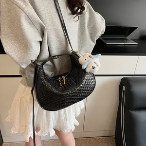 Detail of black woven crescent bag with gold zipper and white plush cloud charm