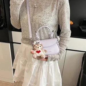 Détail du sac bandoulière lilas avec charm ourson et logo embossé sur le devant