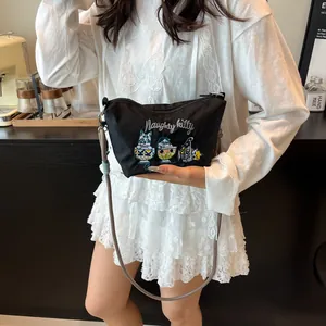 Detail of embroidered naughty kitty pattern on black nylon crossbody bag for women