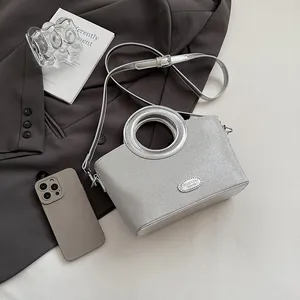 Détail du sac à main argenté avec poignée circulaire en métal et plaque de mode