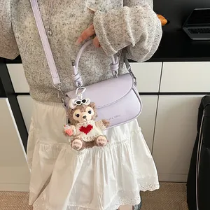 Détail du sac à main en cuir violet clair avec breloque en peluche et bandoulière