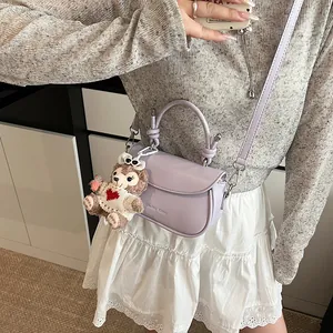 Détail du sac à main en cuir violet clair avec breloque ours et logo embossé chic