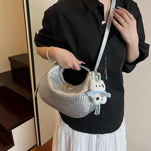Close-up of silver woven hobo bag with gold zipper and a cute white teddy bear charm