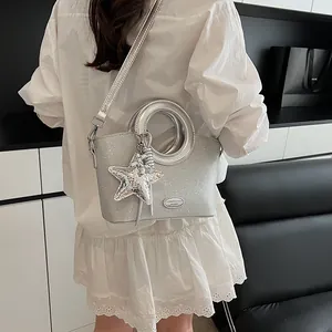 Détail d'un sac seau à paillettes argentées avec poignée ronde et accessoire en étoile