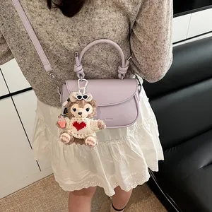 Détail du sac en cuir lavande avec poignée nouée et charmant pendentif ours en peluche