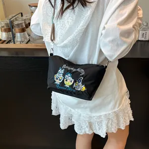 Detail of embroidered cats and text on black nylon shoulder bag with adjustable strap