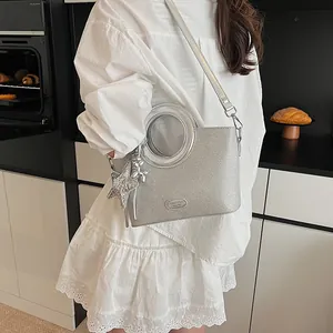 Détail du sac argenté scintillant avec poignées rondes et pendentif en forme de chien
