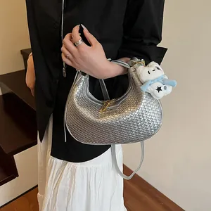 Detail of silver woven hobo bag with gold zipper and cute white teddy bear charm