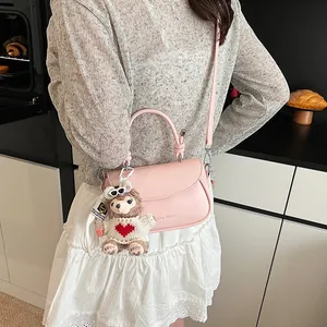 Détail du sac bandoulière rose en similicuir avec un joli pendentif lapin en peluche