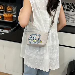 Detail of grey crossbody bag featuring cat embroidery and adjustable brown knotted strap