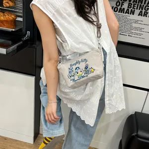 Detail of grey crossbody bag featuring colorful cat embroidery and knotted shoulder strap