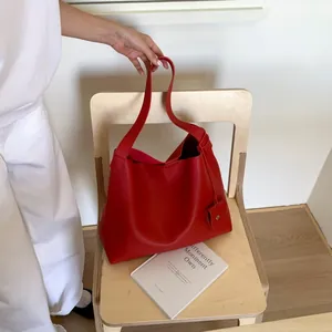 Macro shot of red lychee texture leather tote bag on wooden chair with a heart charm