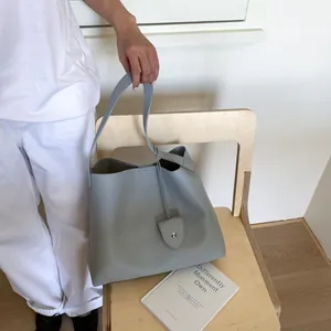 Close-up of light grey lychee pattern leather tote bag with silver rivet detail