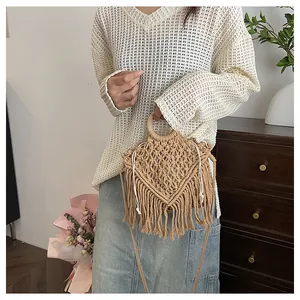 Detail of bohemian hand-woven beige bag featuring cotton tassels and round wooden handles