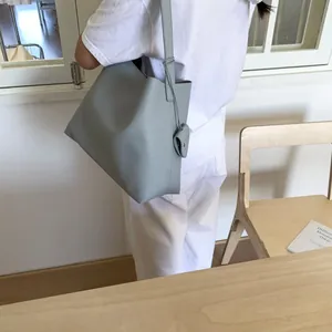 Detail of light blue tote bag with lychee texture and heart-shaped pendant accessory