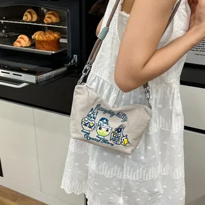 Detail of crossbody bag with cat embroidery and thick rope strap in modern kitchen setting