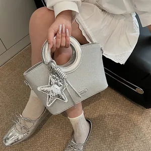 Détail du sac seau à paillettes argentées avec poignée ronde en métal et breloque étoile