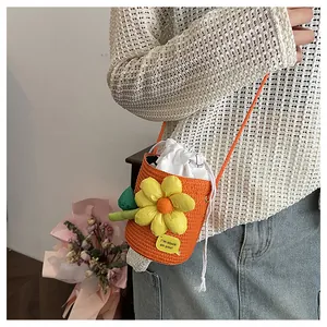 Dettaglio macro della borsa a secchiello intrecciata arancione con girasole 3D giallo