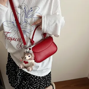 Détail du petit sac carré rouge avec poignée nouée et charmant pendentif ours en peluche