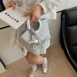Détail du sac seau argenté pailleté avec poignée ronde en métal et breloque étoile style Y2K
