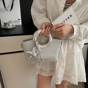 Détail du sac à main pailleté argenté avec breloque étoile et poignée ronde évidée
