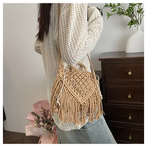 Close-up of beige bohemian woven bag with wooden handles and long decorative tassels