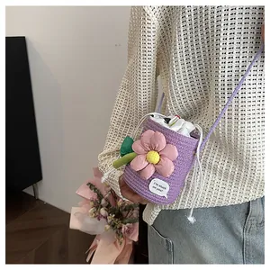Dettaglio della borsa a secchiello viola intrecciata con fiore 3D e etichetta testo