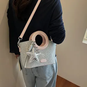 Détail du sac seau à paillettes argentées avec anses en cuir rose et étoile