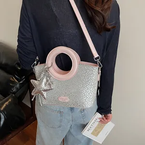Détail du sac seau argenté avec anses roses, motif léopard et breloque en étoile