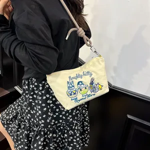 Detail of a beige canvas bag showing delicate cat embroidery and woven rope shoulder strap