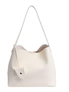 Minimalist beige tote bag in lychee pattern leather with shoulder strap and charm