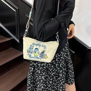 Detailed close-up of a cream canvas crossbody bag with delicate cat theme embroidery