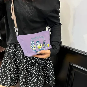 Detail of purple fabric crossbody bag featuring cute embroidered cats and woven rope strap