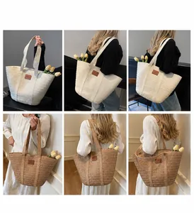 Détail de sacs cabas en paille tressée beige et kaki avec écusson décoratif en cuir