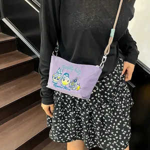 Detail of purple canvas crossbody bag featuring cat embroidery and rope shoulder strap