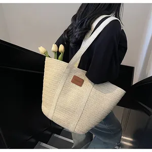 Détail du sac fourre-tout en paille crème avec étiquette en cuir et tulipes jaunes