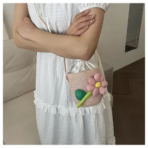 Dettaglio della borsa a secchiello intrecciata con fiori rosa e chiusura a coulisse in raso