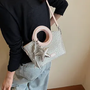 Détail du sac seau argenté à motif léopard avec poignées roses et breloque étoile