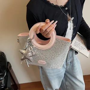 Détail du sac à main à paillettes argentées, motif léopard et poignées roses