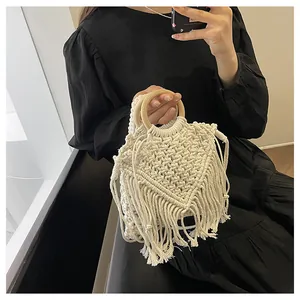 Detail of macrame woven bag showing cotton fiber texture, fringe, and round wooden handles