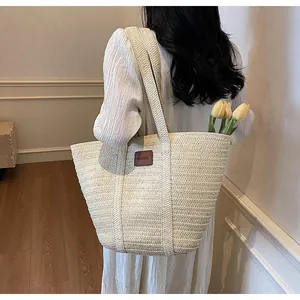 Détail du sac cabas en paille avec étiquette en cuir marron et tulipes jaunes