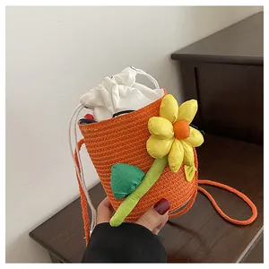 Vista dettagliata di una borsa a secchiello in paglia arancione con fiori 3D
