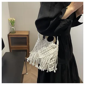 Detail view of a white bohemian woven bag featuring long tassels and wooden handles