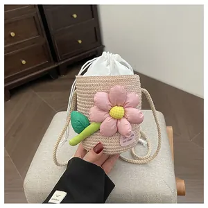 Dettaglio dei fiori rosa e della chiusura a coulisse di una borsa a secchiello in paglia